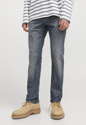 Ljusblå denimjeans med rak passform, kombinerat med beige snörboots med en robust sula. Randig långärmad skjorta.