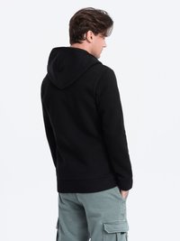 Zwarte hoodie met een gestructureerde afwerking, voorzien van een kangoeroezak, geribde manchetten en een relaxte pasvorm. Draag het met groene cargobroeken.