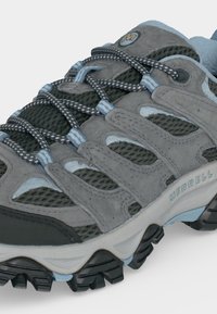 Chaussure de randonnée Merrell grise et noire avec des accents bleus, des panneaux en mesh, une semelle épaisse à crampons et des lacets à motifs.