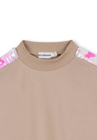 Maglione beige con colletto a girocollo a coste e strisce di paillettes rosa, bianche e argentate sulle spalle, con etichetta BILLIEBLUSH all'interno del colletto.