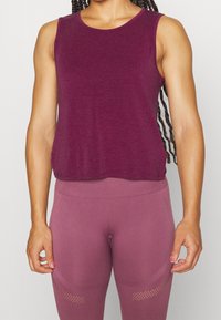 Livlig lila linne av mjukt tyg, med en lös passform och rundad halsringning; ihopsatt med matchande åtsittande leggins.