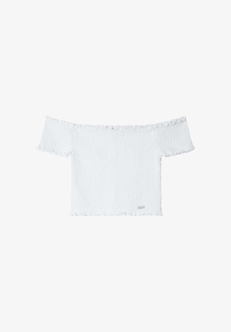 Valge õlad paljastav topp, mis on valmistatud tekstureeritud kangast, volangidega servades ja lühikeste varrukatega. Aluseosas on väike logo silt.