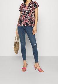 Květinová blůza s krátkými rukávy, námořnický modrý podklad, růžové a bílé květiny. V kombinaci s modrými úzkými džíny a růžovými lodičkami na vysokém podpatku.