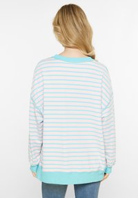 Pullover a righe nei toni del rosa e azzurro chiaro, con maniche lunghe, scollatura rotonda e una morbida texture di cotone. Decorato con un orlo blu.