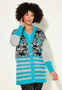 Cardigan colorato con un motivo nero e grigio, dettagli turchesi e bottoni grandi. Sezioni a righe sulle maniche e sul corpo.