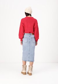 Röd texturerad stickad tröja, ljusblå denim midi-kjol med fickor, och beige kängor med pälsfoder och kraftiga sulor.