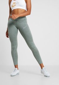 Ljusgröna, åtsittande leggings med en texturerad yta och perforerade paneler vid underbenen; med en liten grå Nike-logga på låret.