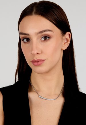 Collana d'argento con un pendente curvo decorato da una fila di gemme scintillanti, montata su una delicata catena, esposta su un modello contro uno sfondo neutro.