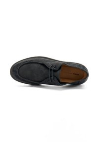 Zapato de ante negro con cordones, que presenta una punta redondeada y detalles de costura, descansando sobre un fondo blanco.