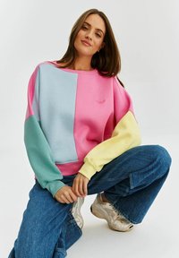 Bluza w kolorowe bloki, z różowymi, niebieskimi, zielonymi i żółtymi panelami, o miękkiej fakturze i subtelnym haftem na wysokości dekoltu.
