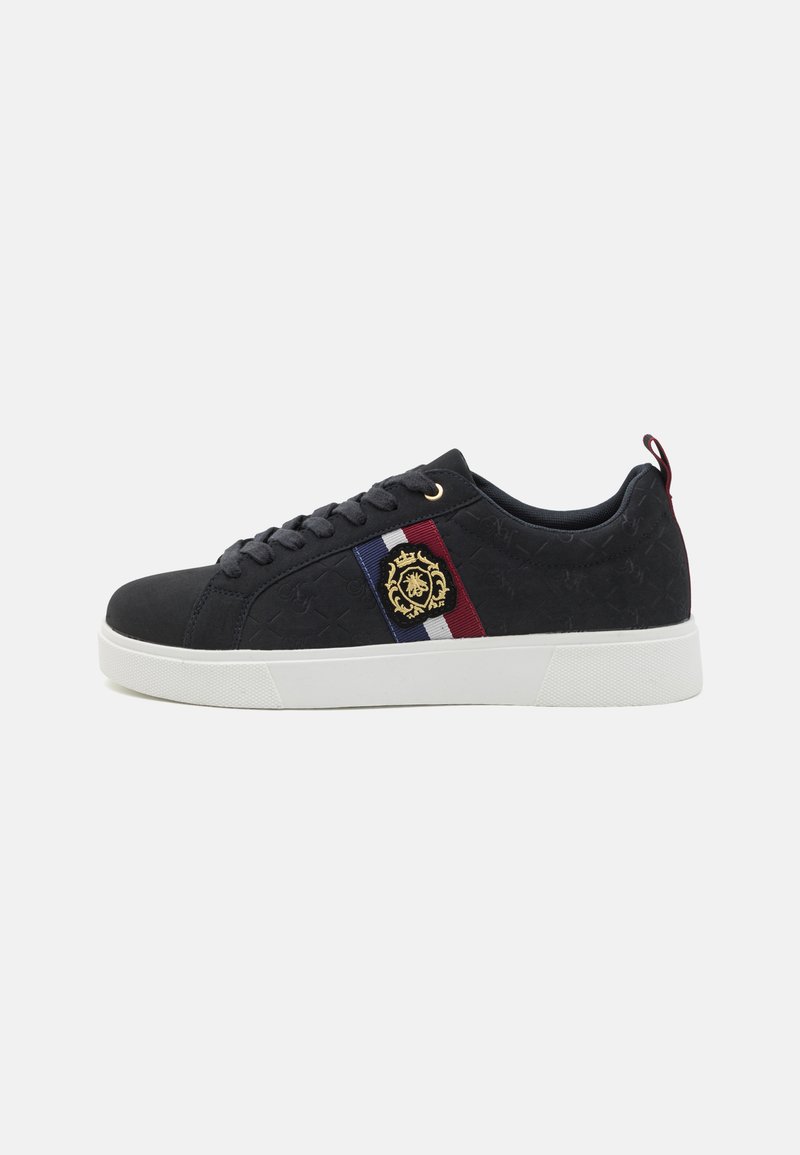 Sneaker noir avec une tige texturée, présente un emblème doré, un accent rayé en bleu, blanc et rouge sur le côté, et une semelle extérieure blanche.