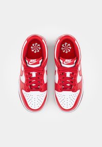 Piros és fehér Nike sportcipők, bőr felső résszel, perforált orral és piros fűzőkkel. Logó a nyelvén és virágmintás talpbetét.