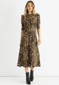 Leopard print dress in beige and black, featuring short puff sleeves, a fitted waist, and a flowing mid-length skirt. Pair with black ankle boots.