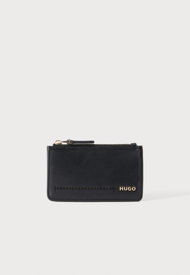 Porte-cartes en cuir noir avec fermeture éclair supérieure et logo doré "HUGO" en bas à droite, sur un fond clair uni.