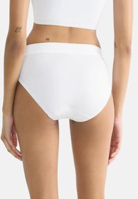 Weiße Baumwollunterhose mit nahtlosem Design, mittelhohem Bund und weichem Gummiband; glatte Textur mit minimalistischer Gestaltung.