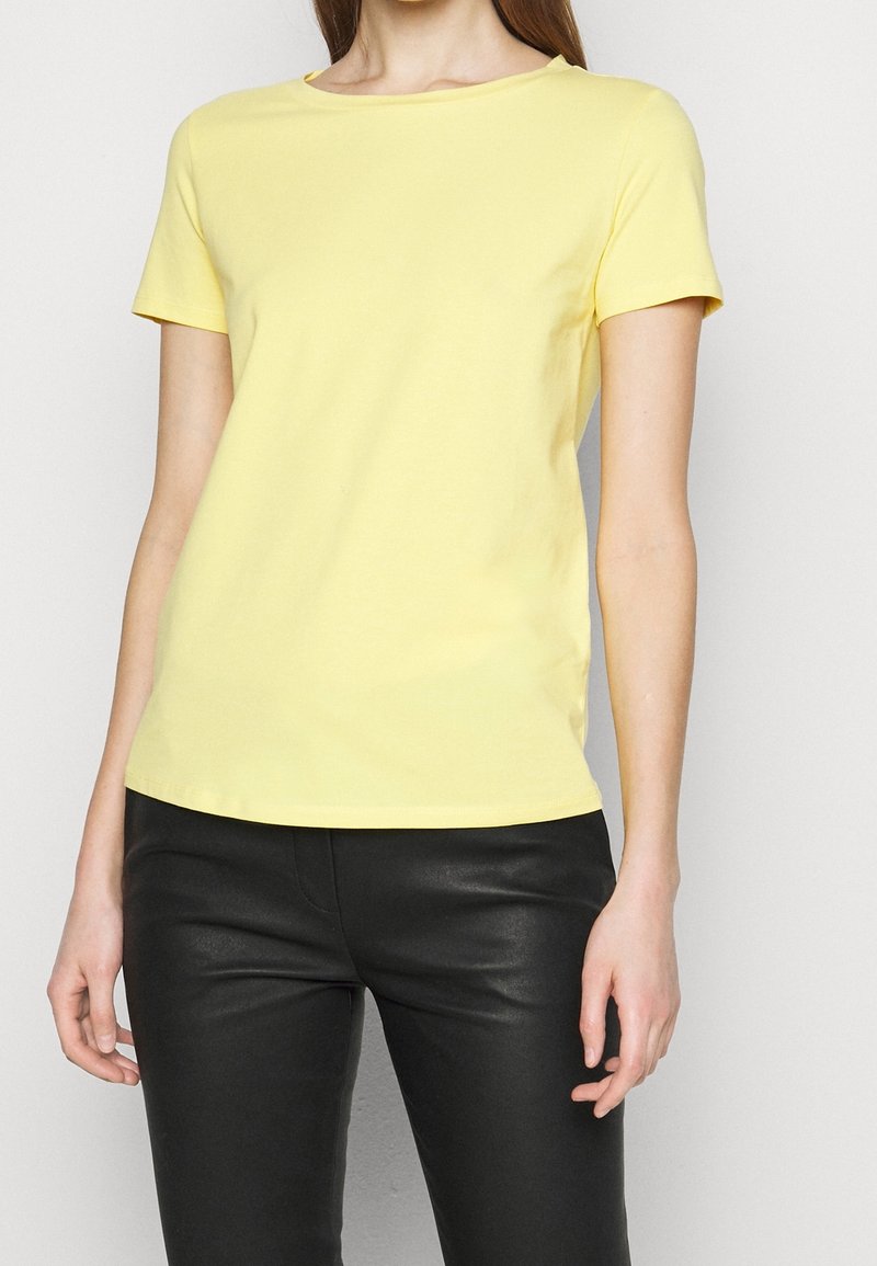 T-shirt en coton jaune à manches courtes et encolure ronde, présentant une texture lisse et une silhouette ajustée.