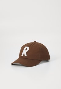 Brown baseball cap made of cotton. Features a white embroidered letter "R" on the front. Structured shape with a curved brim.
