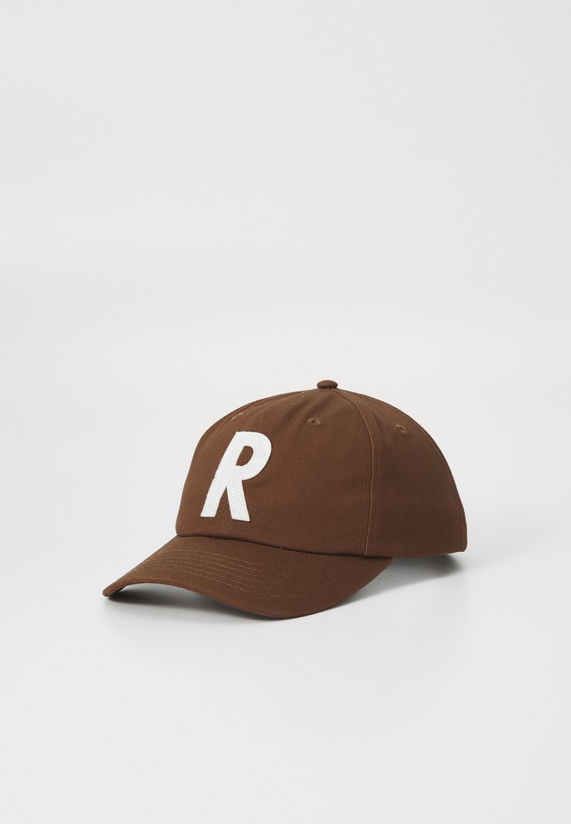 Brown baseball cap made of cotton. Features a white embroidered letter "R" on the front. Structured shape with a curved brim.