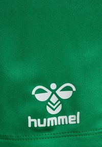 Grön tyg med en texturerad yta, med en vit logotypdesign som liknar en bi och ordet "hummel" nedan.