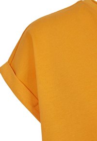 Keltainen puuvillapaita, jossa on pyöreä kaula-aukko ja käännetyt lyhyet hihat. Kankaan pinta on sileä ja väri on kiinteä ja elinvoimainen.