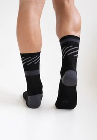 Schwarze Socken mit grauen Akzenten, die über einen gerippten Saum und diagonale Streifen verfügen. Das Material wirkt glatt und dehnbar. Niedrig geschnittenes Design.