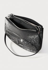 Schwarze synthetische Tasche mit silbernen Beschlägen, ausgestattet mit einem gesprenkelten weißen Muster, zwei Reißverschlusstaschen und einem schmalen verstellbaren Riemen.
