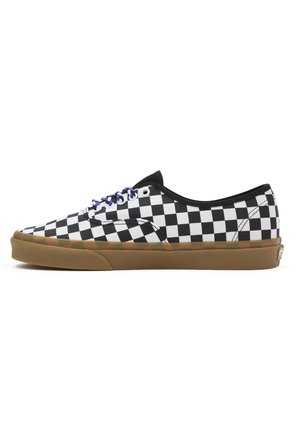Baskets basses avec motif damier noir et blanc, lacets bleus, bordure noire et semelle en gomme marron sur fond blanc.