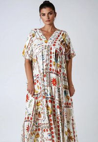 Witte maxi-jurk met levendige, kleurrijke patronen met bloem- en symbolische ontwerpen. V-hals en korte mouwen, gemaakt van lichtgewicht stof.