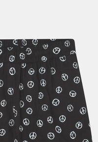 Čern�é látkové šortky s potiskem bílé symboly míru. Vybaveny elastickým pasem a lehkou strukturou, navrženy pro pohodlí a volný čas.