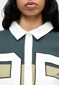 Βαμβακερό πόλο πουκάμισο με λευκό γιακά, πράσινο και κρεμ γεωμετρικό σχέδιο, με τρισδιάστατο αριθμημένο μοτίβο σε μαύρο περίγραμμα.