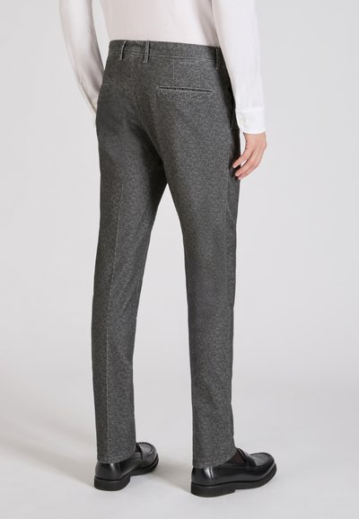 Szare spodni o teksturze i dopasowanym kroju, z elastycznym pasem z szlufkami na pasek oraz detalami tylnych kieszeni, w zestawie z czarnymi butami.