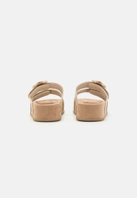 Beige semskede plattform sandaler med doble stropper og en dekorativ spenne, med en tykk, teksturert såle for bedre grep og komfort.