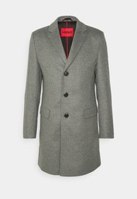 Cappotto grigio in misto lana con rever a sciarpa, tre bottoni neri, due tasche laterali e un'etichetta interna rossa brillante.