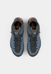 Bottes de randonnée en bleu foncé et noir, présentant un dessus texturé, une semelle en caoutchouc noire et des lacets gris avec des accents orange.