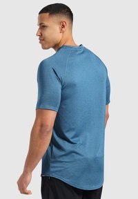 Camisa atlética azul de manga corta con tela texturizada, cuello redondo y costuras en contraste. Ajuste entallado con dobladillo curvado.