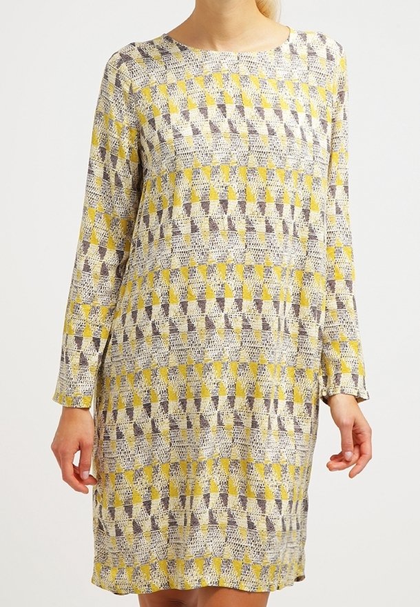 Vestido de manga larga con un patrón geométrico en amarillo y púrpura, hecho de una tela ligera. Presenta un escote redondo y un corte relajado.