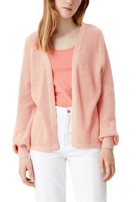 Jasnoróżowy sweter dzianinowy o luźnym kroju, z otwartym przodem, ściągaczami przy mankietach i strukturalną tkaniną, zestawiony z pasującą różową bluzką i białymi spodniami.