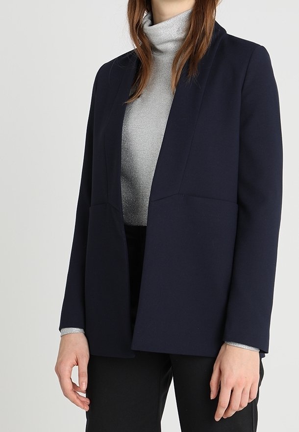 Marinblå kavaj med en strukturerad design, skräddarsydd passform och två framfickor, bärs över en silvrig polokrage. Slät textur, minimalistisk stil.