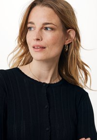 Černý pletený cardigan se zvlněným výstřihem, vertikálním žebrováním a kulatými knoflíky. Obsahuje strukturovanou, prodyšnou látku a přiléhavý střih.