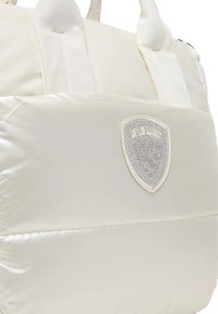 Borsa tote imbottita color bianco sporco con manici corti e un emblema testurizzato a forma di scudo sul davanti.