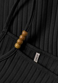 Un pezzo di tessuto nero a coste con una stringa regolabile decorata da tre perline di legno. L'etichetta del marchio "ONLY" è visibile vicino al bordo inferiore.