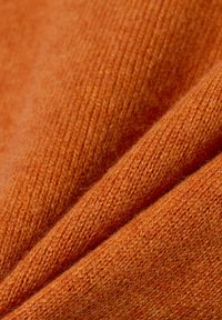 Strukturierter Wollstoff in tiefem Orange; glatte Oberfläche mit subtilen Variationen, die ein weiches und warmes Erscheinungsbild zeigen.