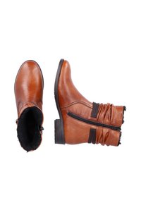 Braune Lederknöchelstiefel mit flachem Absatz, seitlichem Reißverschluss und gerafftem Stoffdetails am Schaft. Flausches Futter sichtbar.