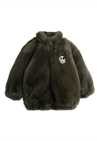 Olivengrønn faux fur jakke med høy krage, store ermer og en rundlapp med et tegneserie-skjelett i midten. Gullmaskindetaljer.