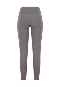 Leggings gris en tissu extensible et lisse, avec une taille haute et une silhouette ajustée, présentant des détails de couture minimalistes.