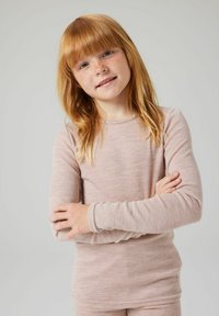 Długi rękaw, prążkowany top w jasnoróżowym kolorze, z okrągłym dekoltem i dopasowanym krojem. Modelka ma długie, proste blond włosy.