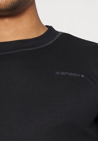 T-shirt nera a girocollo realizzata in tessuto morbido e stretch. Presenta un dettaglio del logo discreto e cuciture piatte per un look elegante.