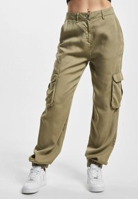 Kaki cargo bukser laget av bomull, med sidelommer, en avslappet passform, elastiske mansjetter og knappelukking i livet. Kombinert med hvite joggesko.