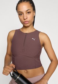 Καφέ αθλητικό crop top με φερμουάρ, με λογότυπο PUMA, σε συνδυασμό με ανοιχτόχρωμο σορτς και μαύρο παγούρι νερού.