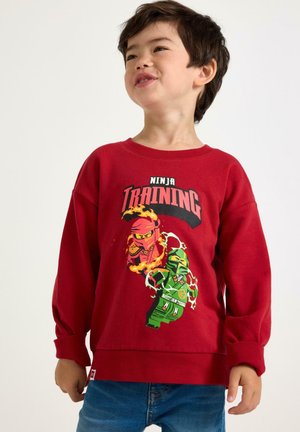 Sweatshirt rouge avec un col rond et des manches longues, présentant un graphique de personnages ninja dans des couleurs vives, fabriqué en tissu doux.